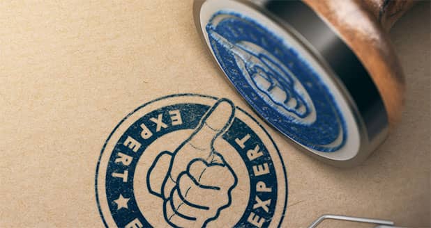 Blue rubber stamp saying expert with a thumbs up printed on brown paper